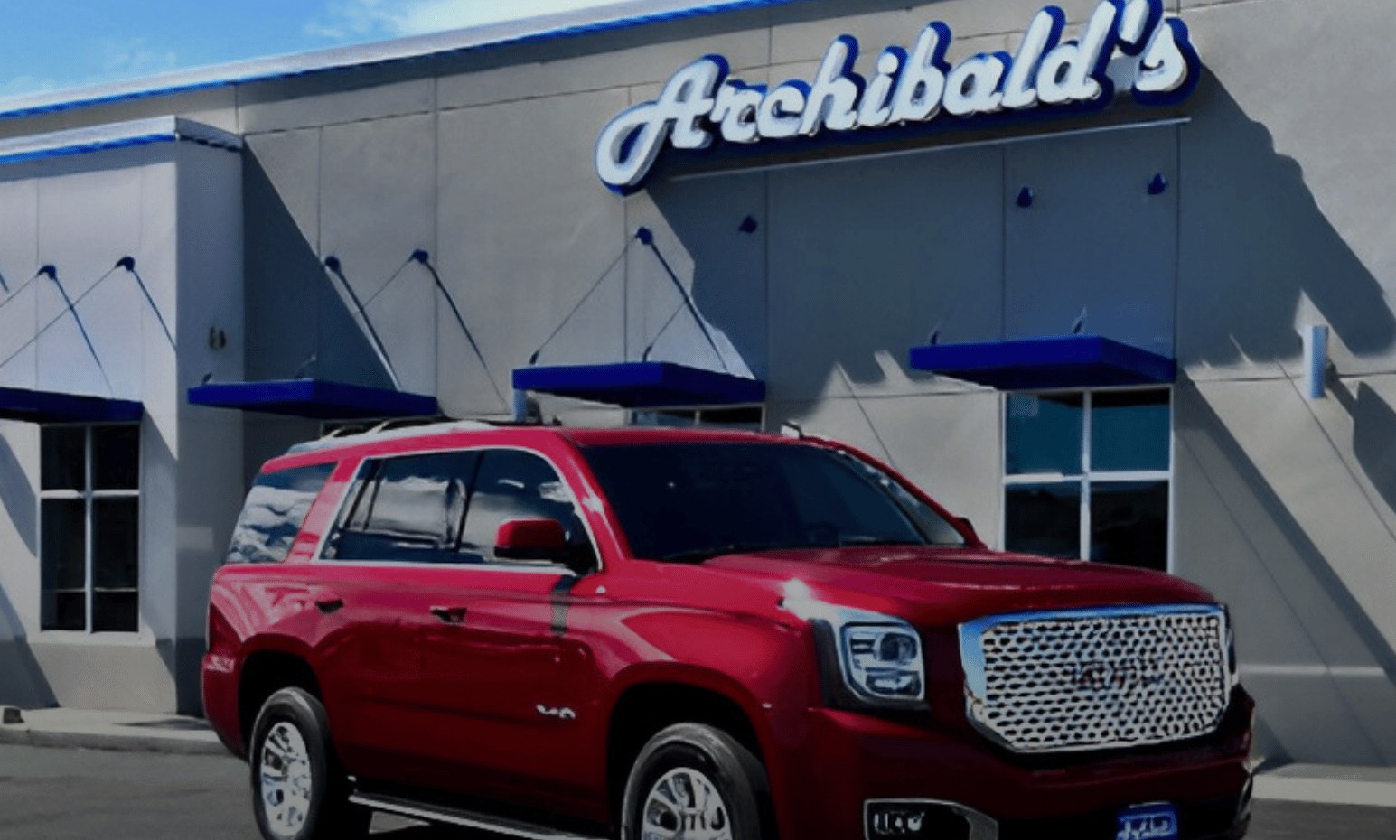 Archibald's dealership storefront with a red GMC Yukon out front